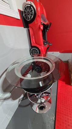 a red toy car sitting on top of a glass table