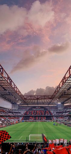 an empty soccer stadium filled with people watching the game at sunset or sunrise, as seen from the stands