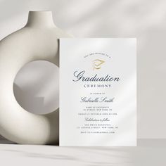 a white vase with a graduation ceremony card in it