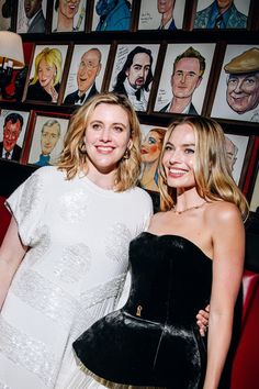 two women standing next to each other in front of pictures