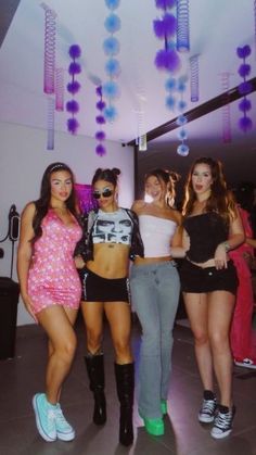 four women in short skirts and high heels posing for the camera with one woman standing behind her