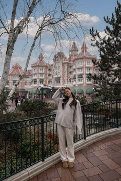 a woman standing in front of a building with trees on the other side of it