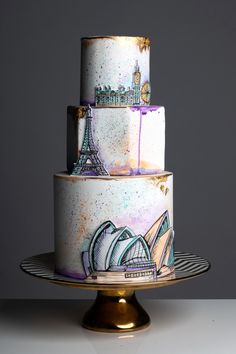 a three tiered cake with the eiffel tower painted on it