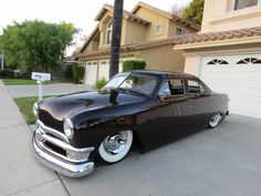 an old black car parked in front of a house