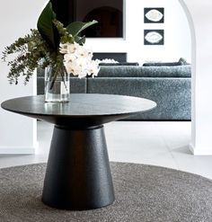 a vase with flowers sitting on top of a table in front of a couch and coffee table