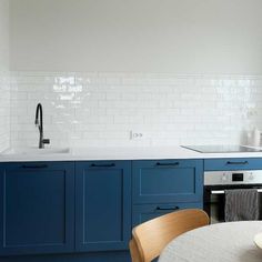 a kitchen with blue cabinets and white subway backsplash