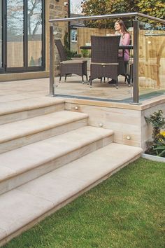 a woman sitting at a table on top of a set of steps next to a patio