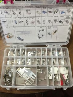 an open plastic case filled with lots of different types of sewing tools and accessories on top of a wooden table