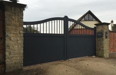 an iron gate and brick wall in front of a house