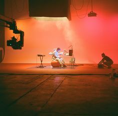 two people sitting on chairs in front of a red light and some lights behind them