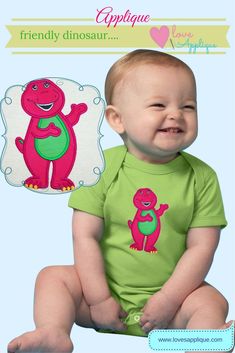 a baby sitting on the ground wearing a green shirt with a pink dinosaur applique