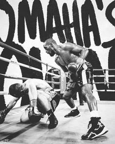 two men in the middle of a boxing ring, one is on the ground while the other