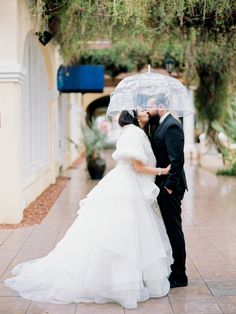 a bride and groom kissing under an umbrella