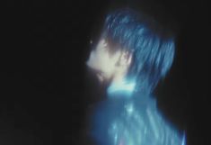 a blurry image of a man with blue hair and piercings in the dark