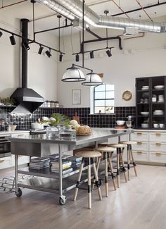 an industrial style kitchen with stainless steel counters and stools in the middle of the room