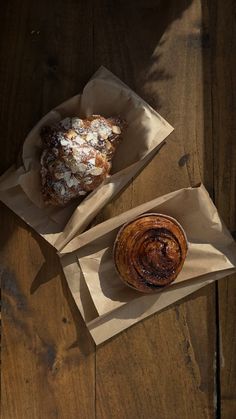 two pastries sitting on top of brown paper bagged in wax paper next to each other