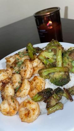 shrimp, broccoli and rice on a plate with a candle in the background