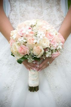 a bridal holding a bouquet of pink and white flowers on her wedding day,