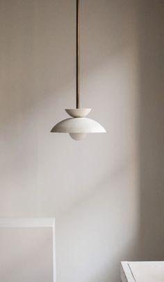 a light fixture hanging from the ceiling in a room with white walls and flooring