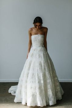 a woman in a white wedding dress standing against a wall