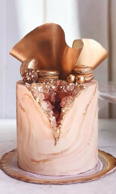 a pink marble cake with gold decorations on it's top and bottom, sitting on a table