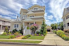 a house with flowers in the front yard and landscaping around it on a sunny day