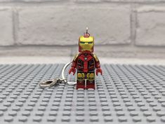 a lego iron man keychain sitting on top of a white table next to a brick wall