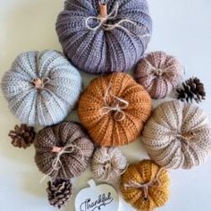 knitted pumpkins and pine cones are arranged together