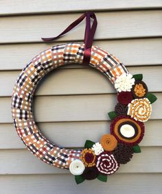 a wreath with flowers is hanging on the side of a house