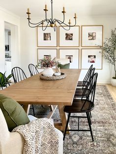 a dining room table with chairs and pictures on the wall behind it, along with an area rug