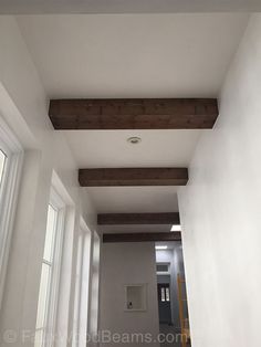 an empty hallway with white walls and wood beams on the ceiling is seen in this image