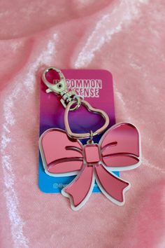 a pink and blue keychain with a big bow on it's side