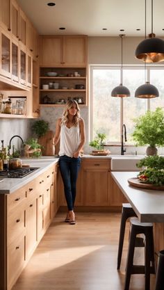 a woman is standing in the middle of a kitchen with wooden cabinets and counter tops