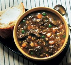 a bowl of beef stew with bread on the side