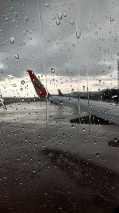 an airplane is seen through the rain covered window