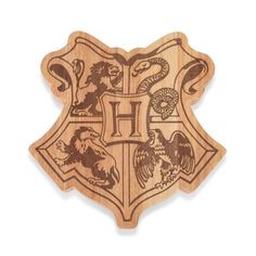 the hogwarts crest is carved from wood and has an eagle, dragon, snake, and letter h on it