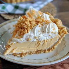 a piece of pie with whipped cream and crumbs on top sits on a plate