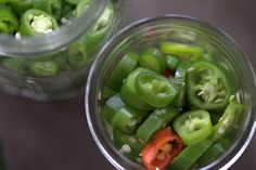 two glass jars filled with green and red peppers