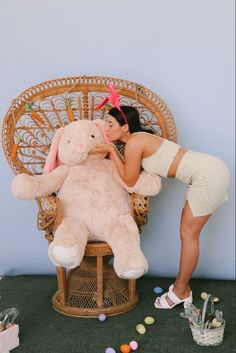 a woman kissing a large teddy bear on top of a chair next to easter eggs