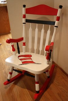 a child's rocking chair with red, white and black paint on the seat