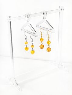 1. These earrings feature round opaque yellow glass upper beads with opaque yellow AB faceted glass lower beads.  Hypoallergenic stainless steel fish hook ear wires.  Earrings come with clear flower earring backers. 2. These earrings feature opaque yellow AB faceted glass upper beads with up-cycled transparent yellow faceted glass lower beads.  Hypoallergenic gold-colored stainless steel fish hook ear wires.  Earrings come with clear flower earring backers. Please keep in mind that colors may vary slightly due to different screen calibrations. Free shipping on orders over $35.  I use Flat Rate Shipping and currently only ship within the U.S. Yellow Czech Glass Dangle Earrings, Yellow Czech Glass Round Bead Earrings, Yellow Dangle Earrings With Faceted Beads, Flower Earring, Steel Earrings, Faceted Glass, Stainless Steel Earrings, Fish Hook, Flower Earrings