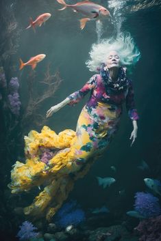 a woman with white hair is swimming in an aquarium surrounded by fish and other marine life