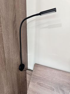 a black handle on a wooden wall next to a white wall and brown wood floor