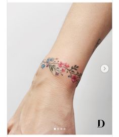 a woman's wrist with a flower tattoo on the left side of her arm