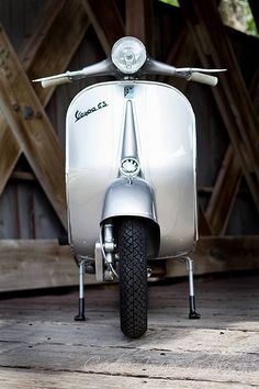 a silver scooter parked on top of a wooden floor next to a building