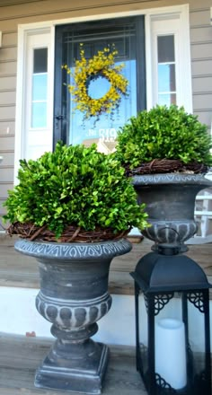 two planters on the front porch with candles and wreaths in them, sitting next to each other