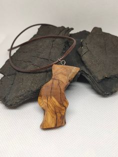 This Olive Wood Necklace pendant was hand carved on our Portuguese Farm from our Olive Trees. These reclaimed wood crafts are one of the many unique handmade jewelry we make. Our Passion and love of nature drives us to create art pieces and sculptures using materials from mother nature. These Unique handcrafted pieces would be a great present or gift idea. Every handcrafted piece is covered in Wax Oil. The black or brown leather cord necklace is about 2mm Thick, and around 50cm long in total. Item 100 - Waves Item 101 - Cliff Natural Wood Pendant Necklace, Artisan Natural Wood Pendant Necklace, Artisan Natural Wood Necklaces, Handmade Artisan Wood Necklaces, Rustic Natural Wood Necklace, Carved Natural Wood Necklaces, Dried Acorns, Wood Necklace Pendant, Tiny Jars