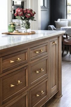 a kitchen island with marble counter tops and gold pulls on the drawers in front of it