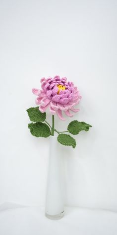 a crocheted pink flower in a white vase