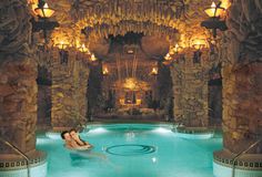 a woman is sitting in the middle of a swimming pool with lights on either side